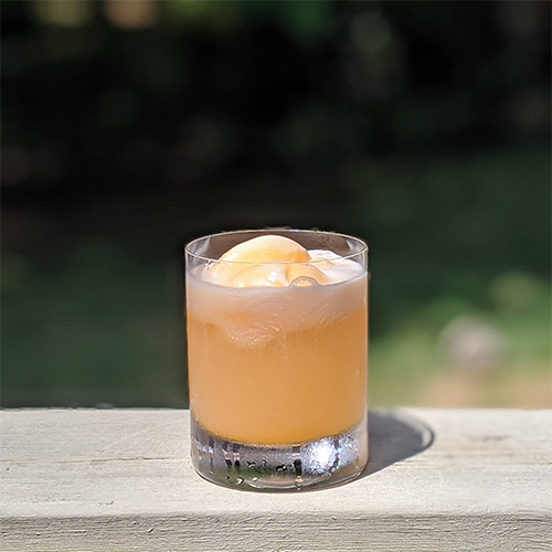 a glass of lemonade with two scoops of orange sherbet